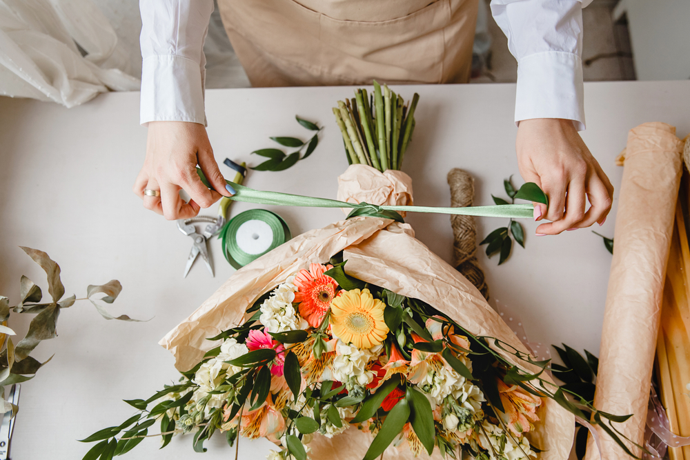 A,female,florist,ties,a,ribbon,bow,on,a,bouquet