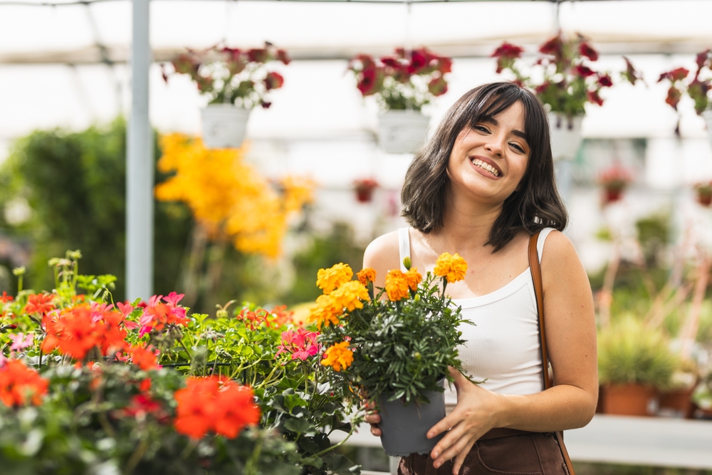 Happy,young,woman,holding,a,vibrant,potted,marigold,while,surrounded