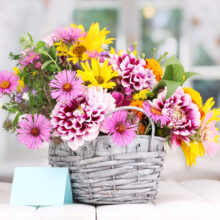 Beautiful,bouquet,of,bright,flowers,in,basket,on,wooden,table