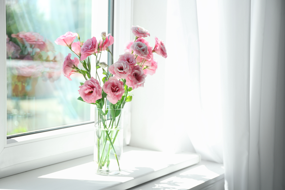 Glass,vase,with,beautiful,flowers,on,window,sill,in,room,