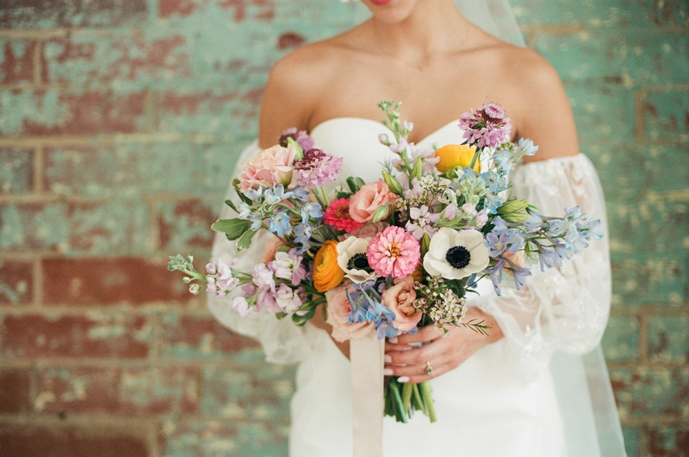 A,bride,holding,a,beautiful,bouquet,of,colorful,flowers,wearing